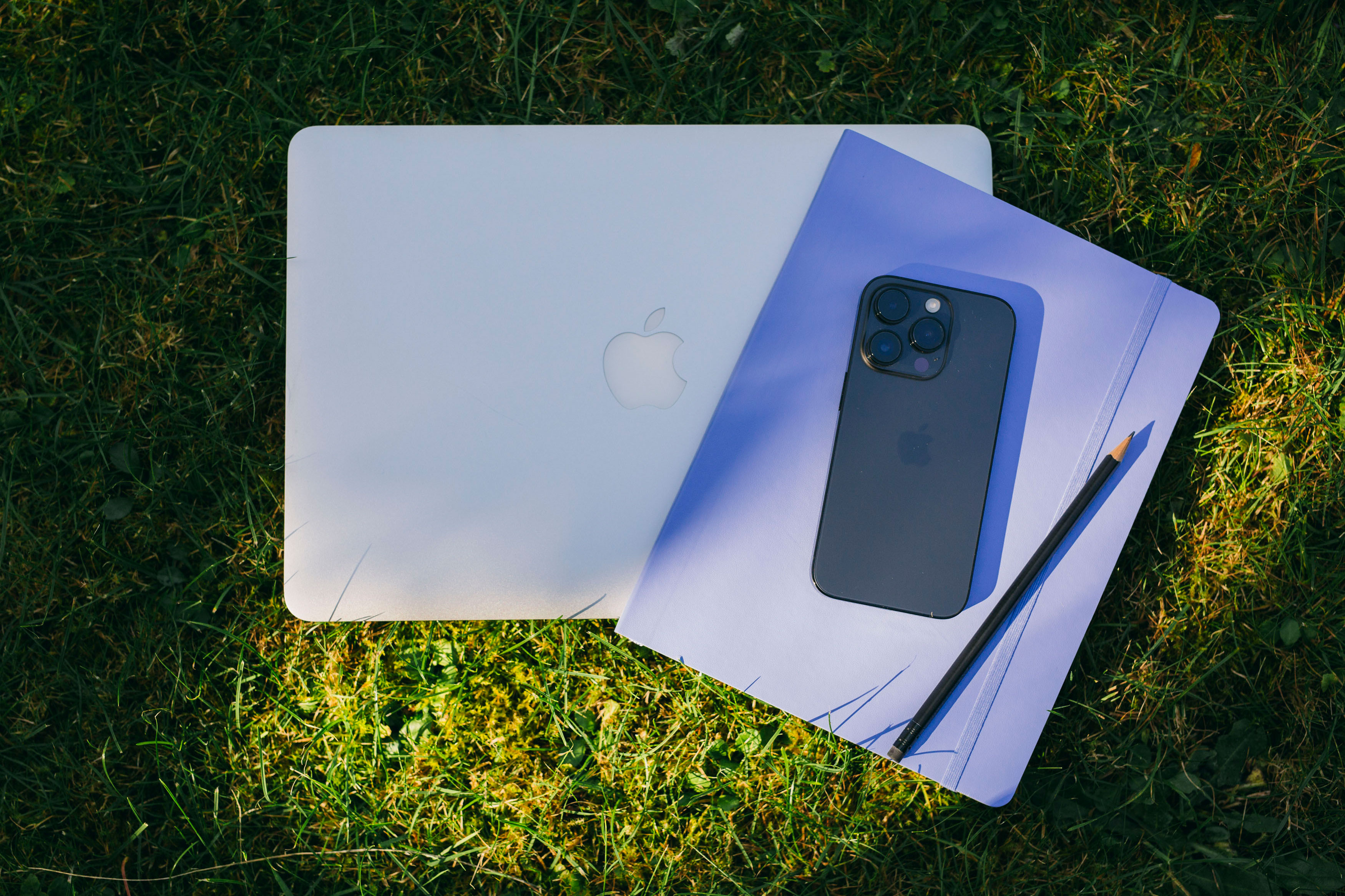 Laptop, Notizbuch, Smartphone und ein Bleistift liefen auf einer Wiese